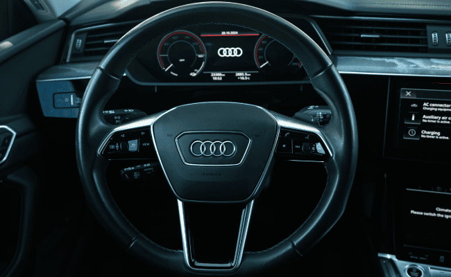 White Audi RS Q8 driving with a retaining wall in the background.