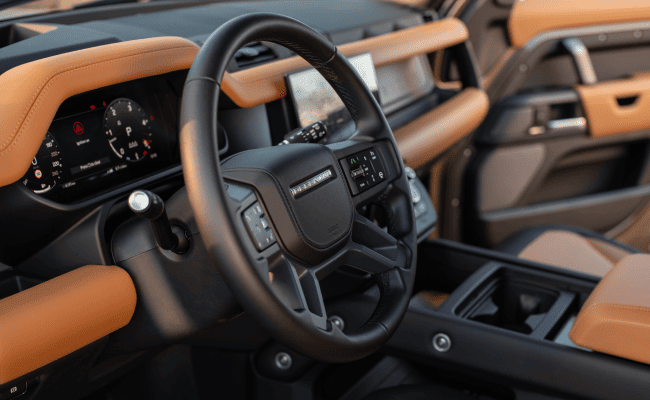 A 2024 Land Rover Defender interior, featuring a premium steering wheel and digital display.