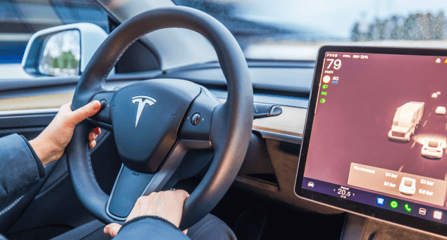 Close-up view of female hands on Tesla Model Y steering wheel with autopilot screen showing road traffic in Charleston, SC.