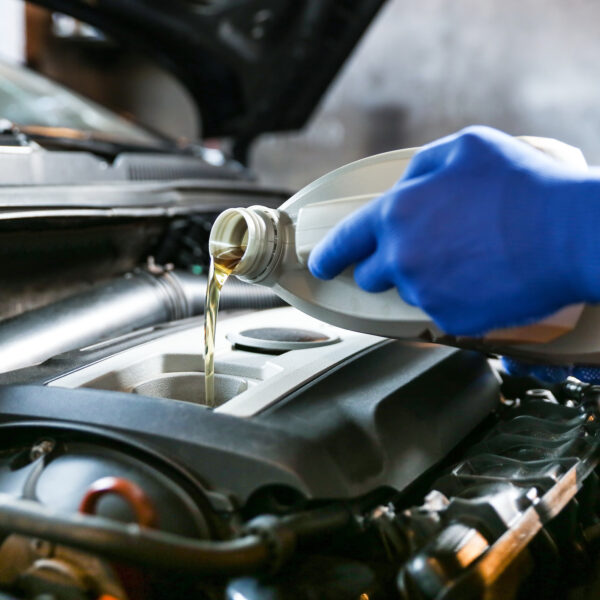 Close up shot of mechanic changing oil on BMW, pouring fresh engine oil into the vehicle's engine.